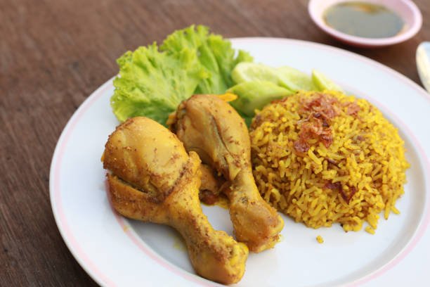 Muslim yellow rice with chicken in a white plate on a wooden floor