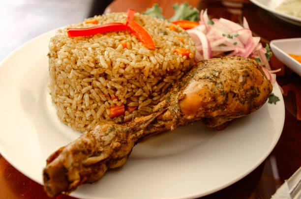 Plate of fried rice with roasted chicken thigh and red onions, served in Lima, Peru